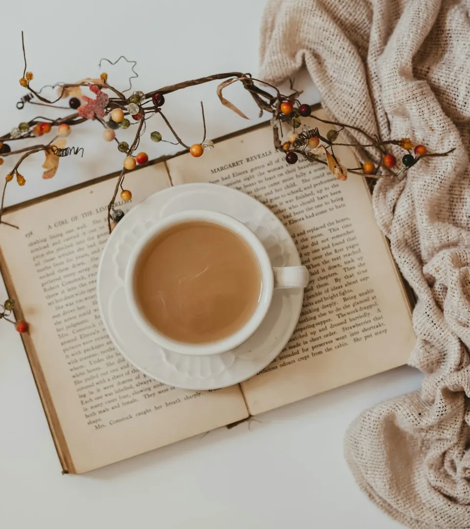 A ceramic cup resting beside an open book.